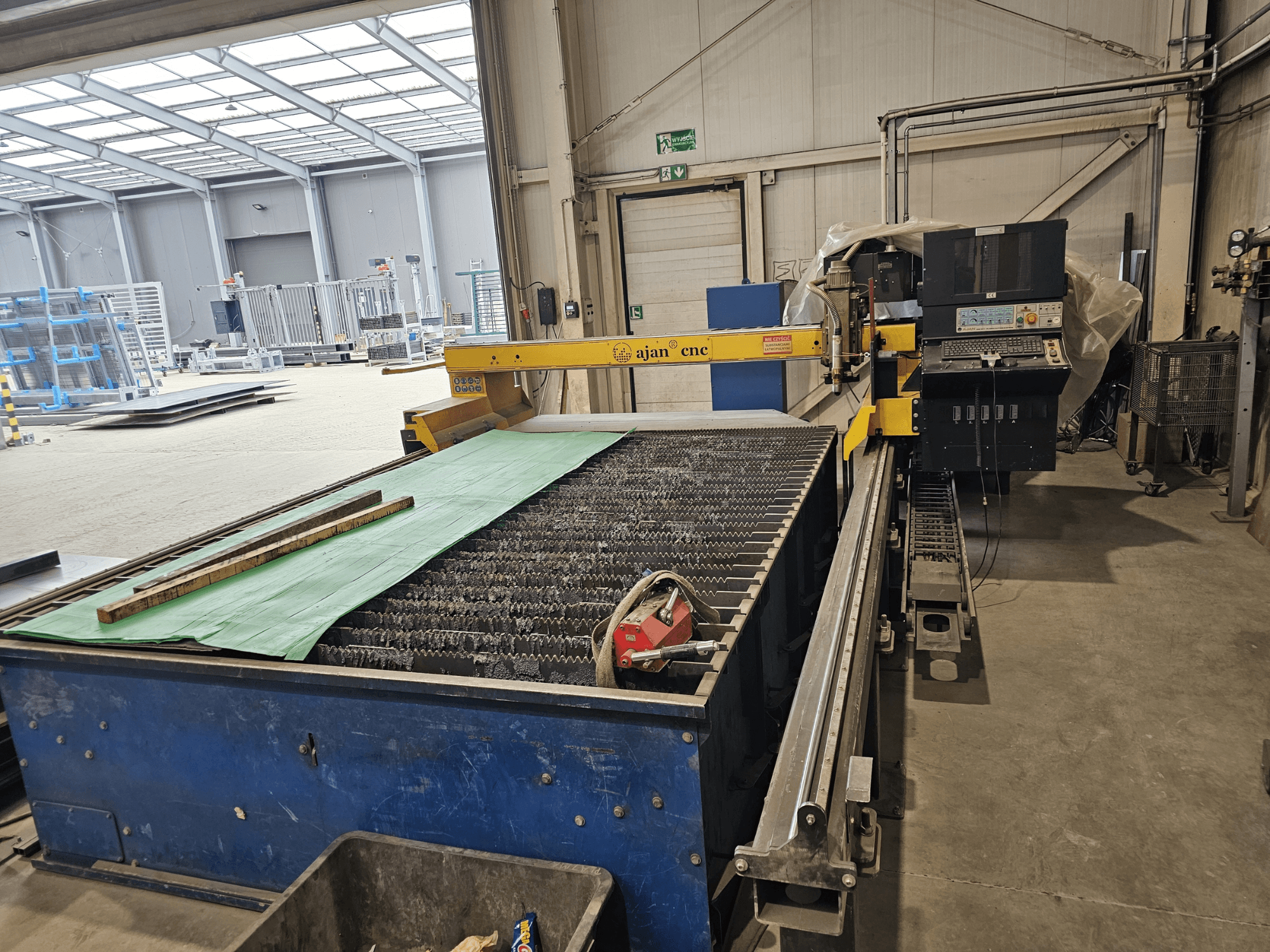 AJAN PP16011 Auto-Plasmaschneidmaschine in Seitenansicht mit Schneidtisch und Bedienfeld in einer Werkstattumgebung.