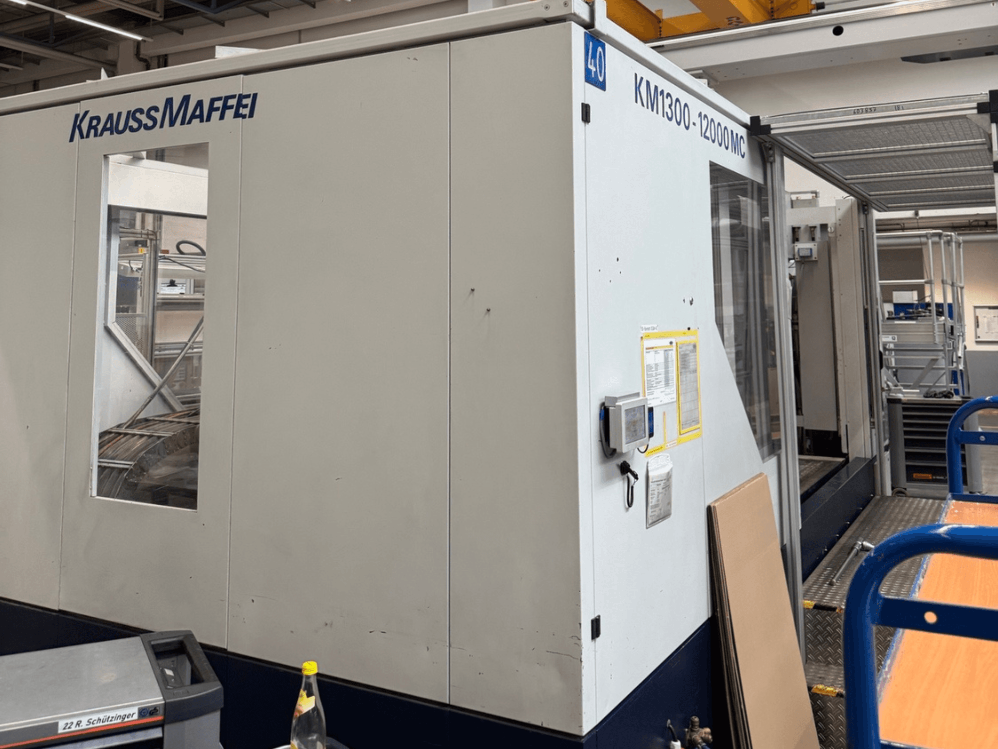 Krauss Maffei Hydraulische Spritzgießmaschine KM1300-12000 MC, Seitenansicht mit Bedienfeld und Arbeitsraum.
