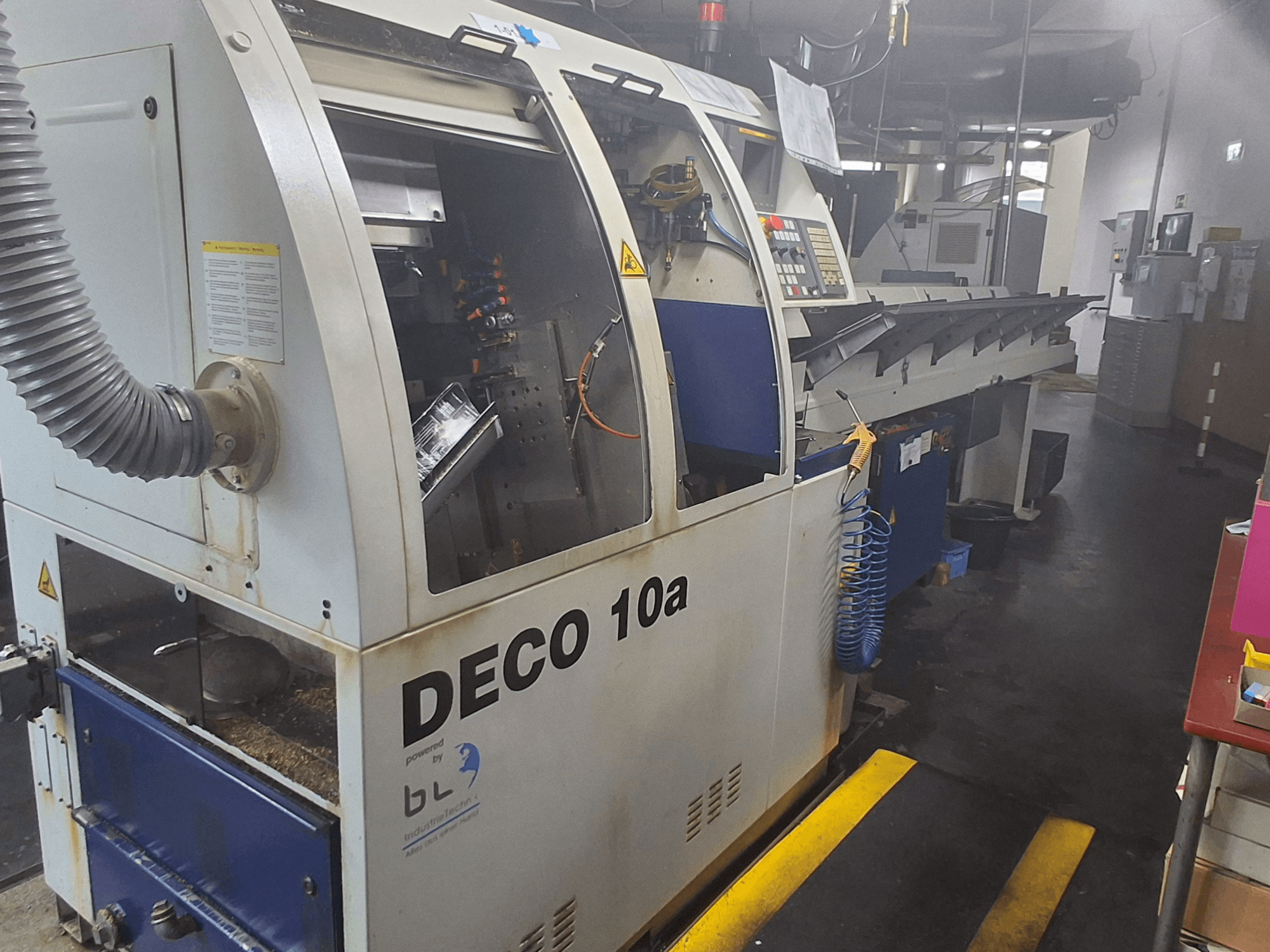 Schweizer Drehmaschine TORNOS DECO 10a, Vorderansicht; mit Bedienfeld, sichtbaren Mechanismen und Absaugrohr.