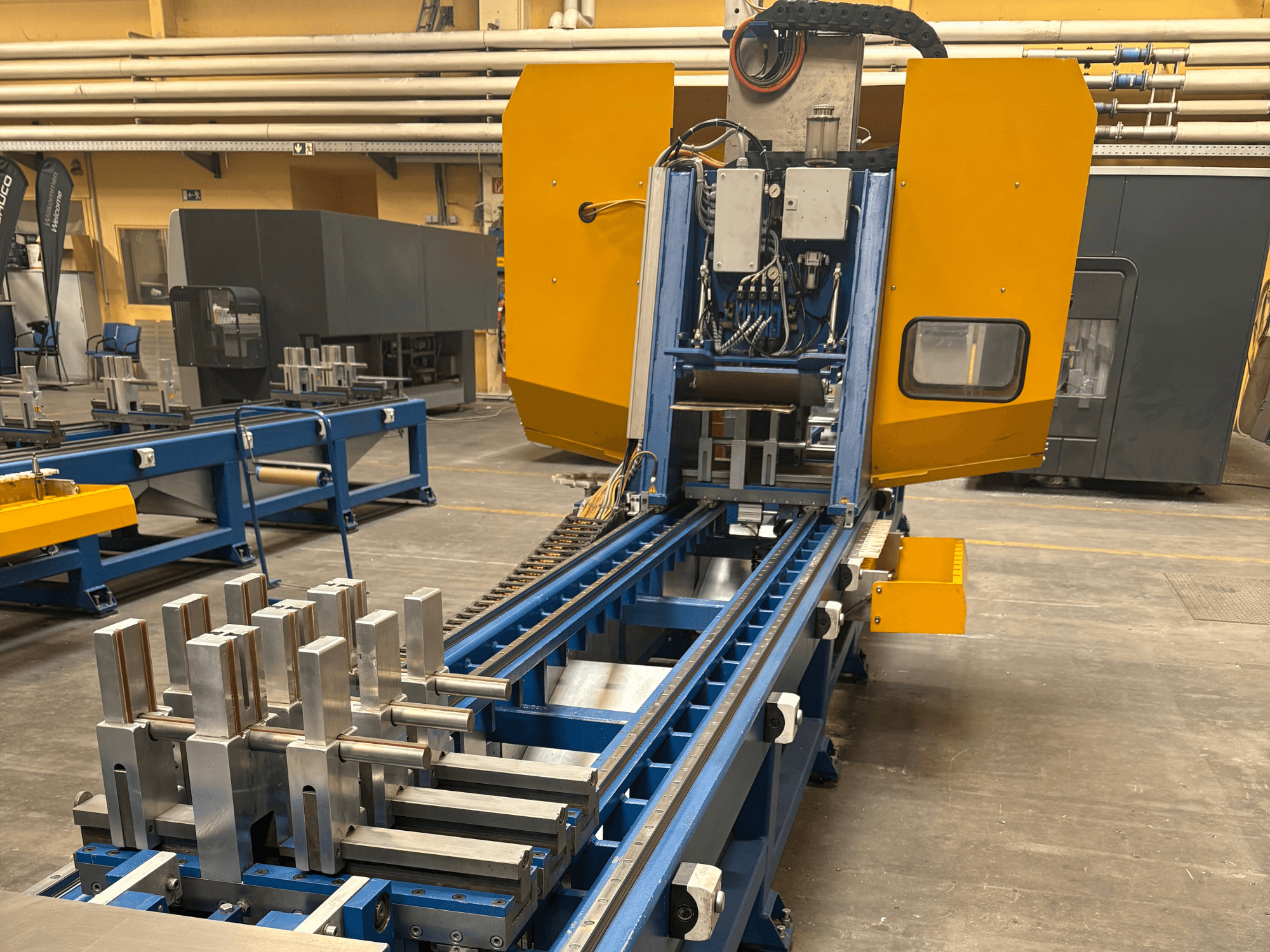 Frontansicht des SCHÜCO PBX AL Universal-Bearbeitungszentrums mit metallischen Werkstücken auf einem blauen Bearbeitungsbett.