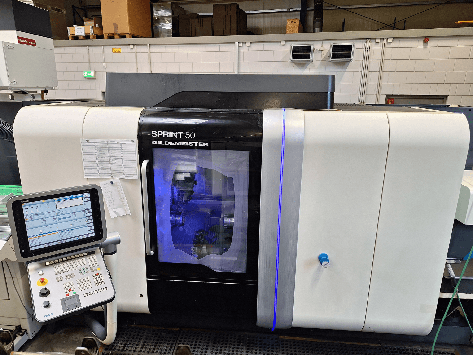 DMG Sprint 50 2T Horizontal-Drehmaschine, Vorderansicht, mit Bedienpult und transparentem Gehäuse, in dem die Maschinen zu sehen sind.