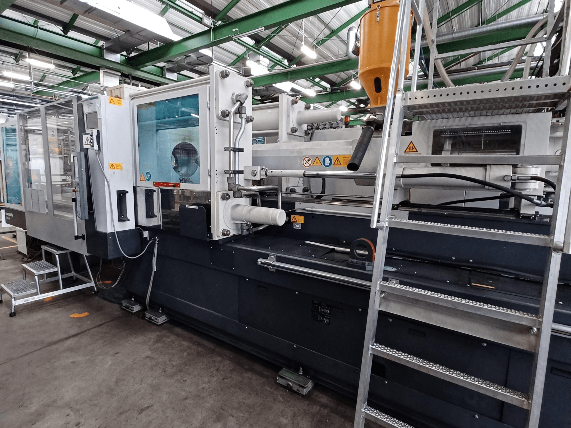 Industrielle Spritzgießmaschine mit klarer Frontansicht, die Markenkennzeichnungen, Bedienfeld und Materialtrichter zeigt.