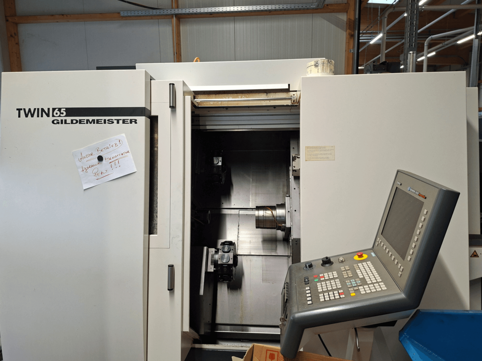 Gildemeister TWIN 65 CNC-Drehmaschine, Vorderansicht mit Bedienfeld und teilweise geöffneter Kammer mit sichtbaren Maschinen.