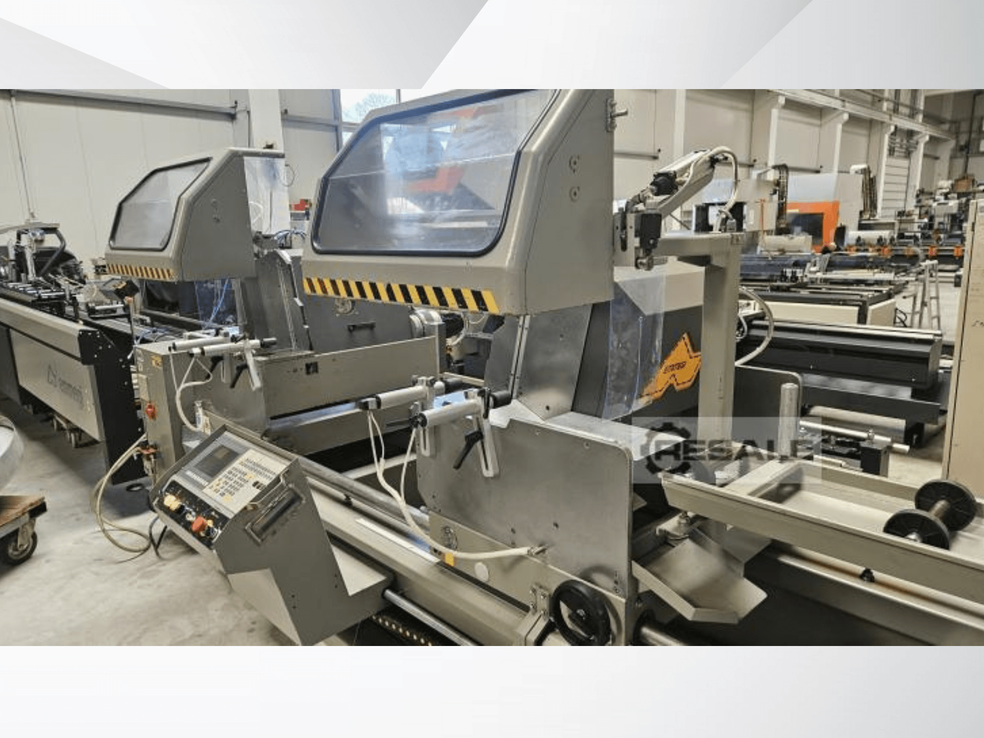 Dual saw machines in a factory setting; front view showing control panel, glass covers, and cutting components.