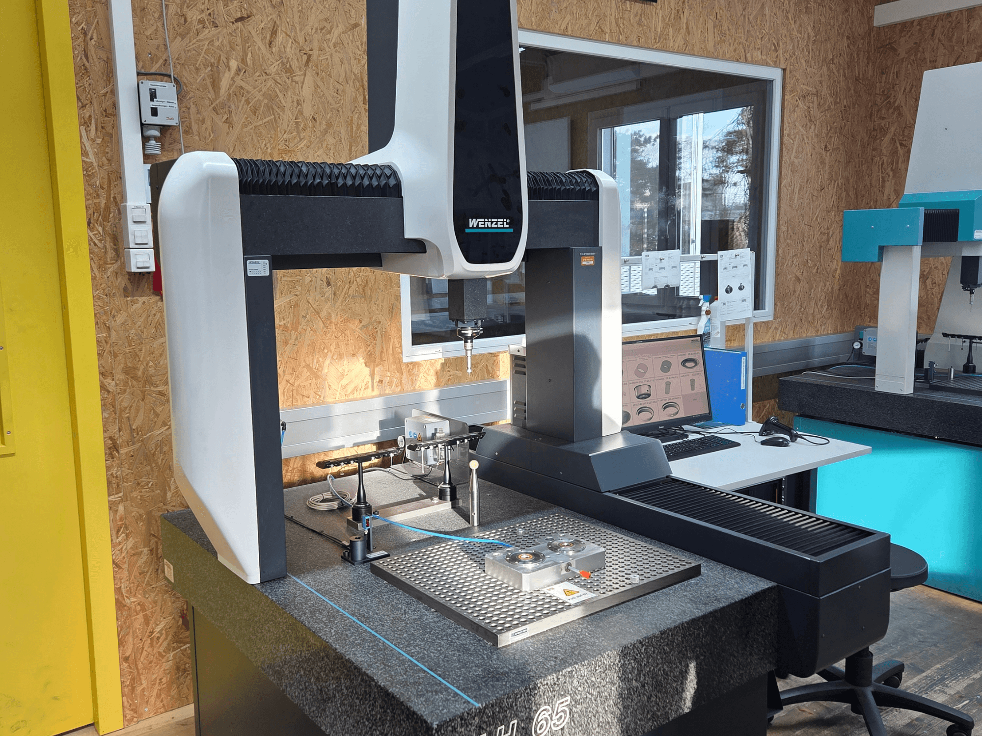 Wenzel-Koordinatenmessgerät LH 65 in einer Laboreinrichtung, Vorderansicht, mit Messwerkzeugen und Monitor.