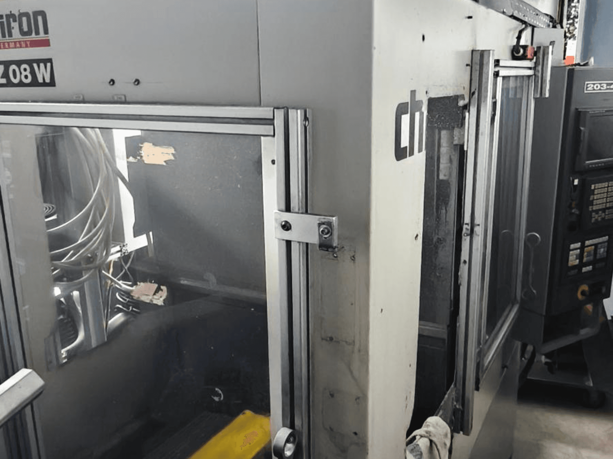 Vertikal-Bearbeitungszentrum CHIRON FZ 08 W, Vorderansicht mit Bedienfeld und teilweise geöffneten Türen, mit sichtbaren Innenkomponenten.