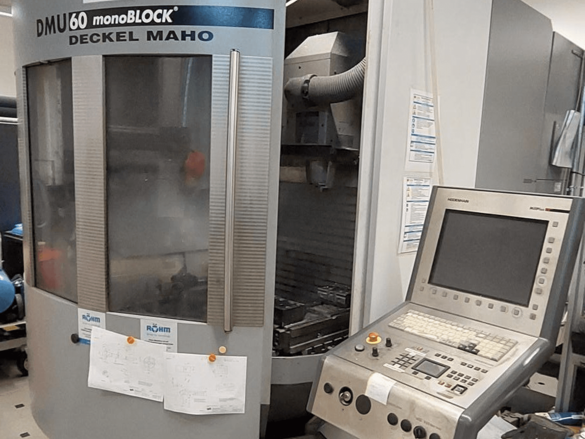 DMU 60 monoBLOCK by Deckel Maho, front view of a CNC milling machine with a control panel and technical drawings attached.