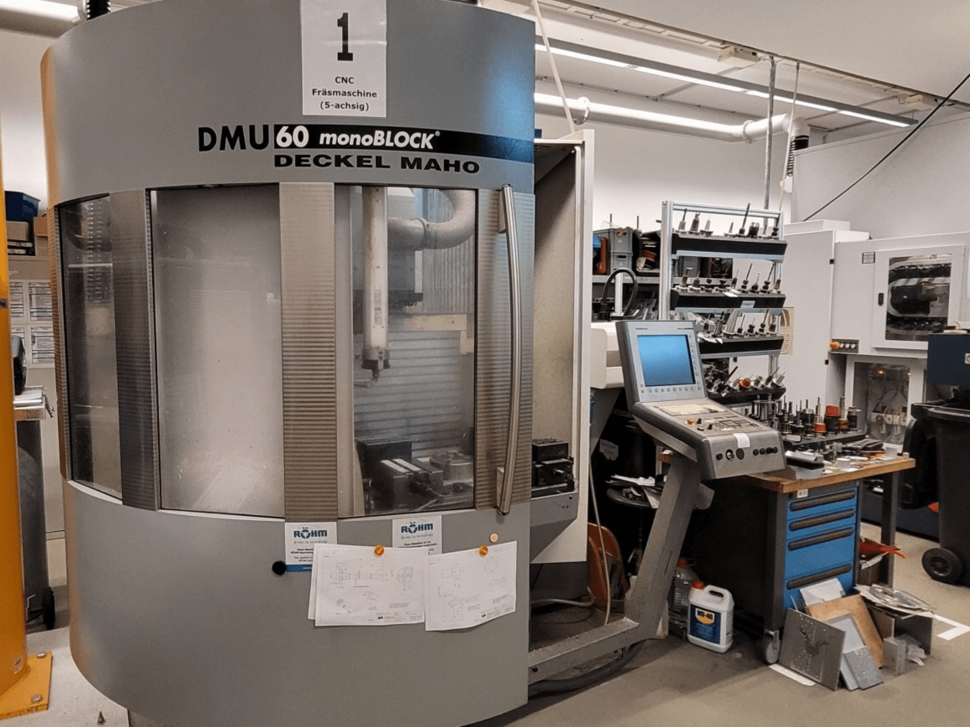 CNC milling machine DECKEL MAHO DMU 60 monoBLOCK in front view, showcasing control panel and tool storage next to it.