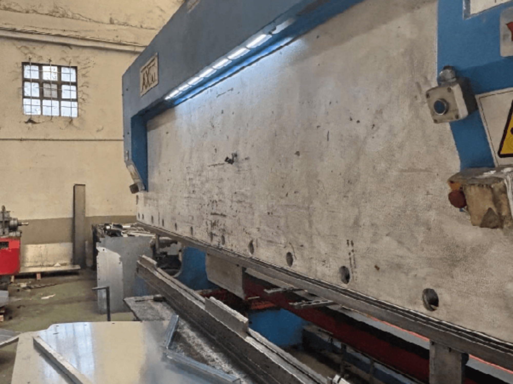 Axial PHS-W-124 Palettenhandhabungssystem in einer Werkstatt, Seitenansicht mit Details der Arbeitsfläche und des Bedienfelds.