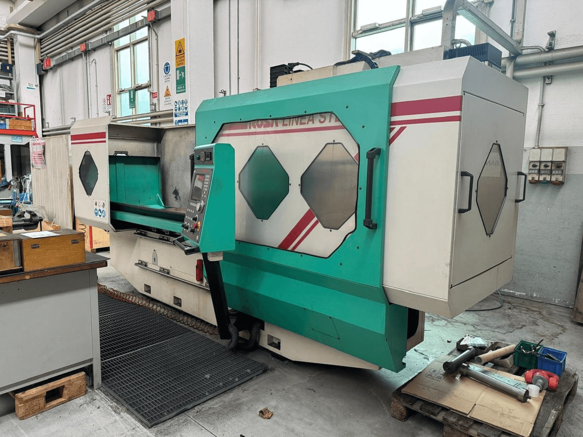 Green and white precision machine, front view, featuring control panel, work area, and tools on a pallet. Brand: BAMB.