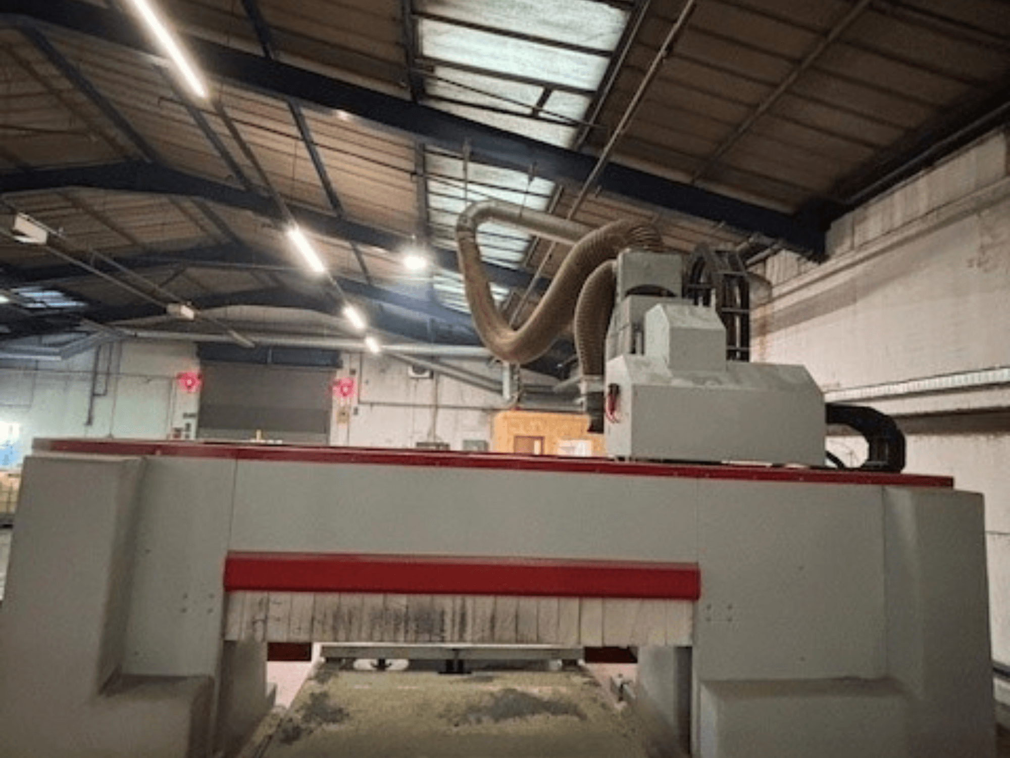 CNC-Fräsmaschine in einer Werkstatt, Seitenansicht mit Hervorhebung des roten und grauen Designs, Staubabsaugung angebracht.