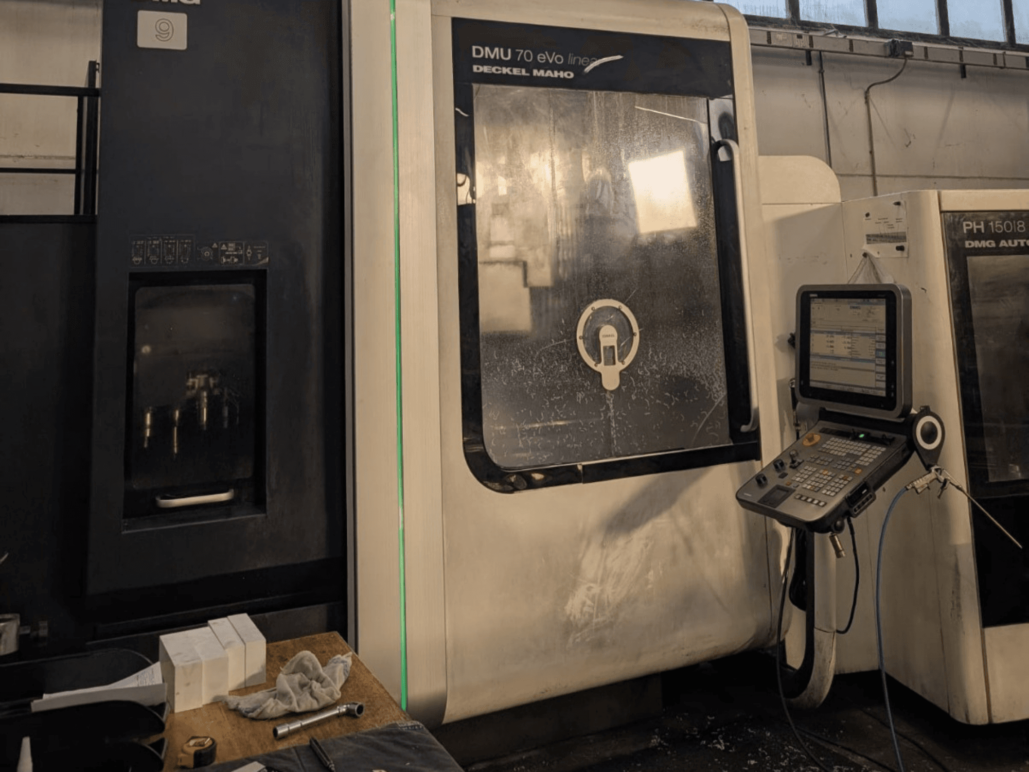 DMG DECKEL MAHO DMU 70 EVO Lineares Vertikal-Bearbeitungszentrum, Vorderansicht mit Bedienfeld, Werkzeugen und Arbeitsraum.