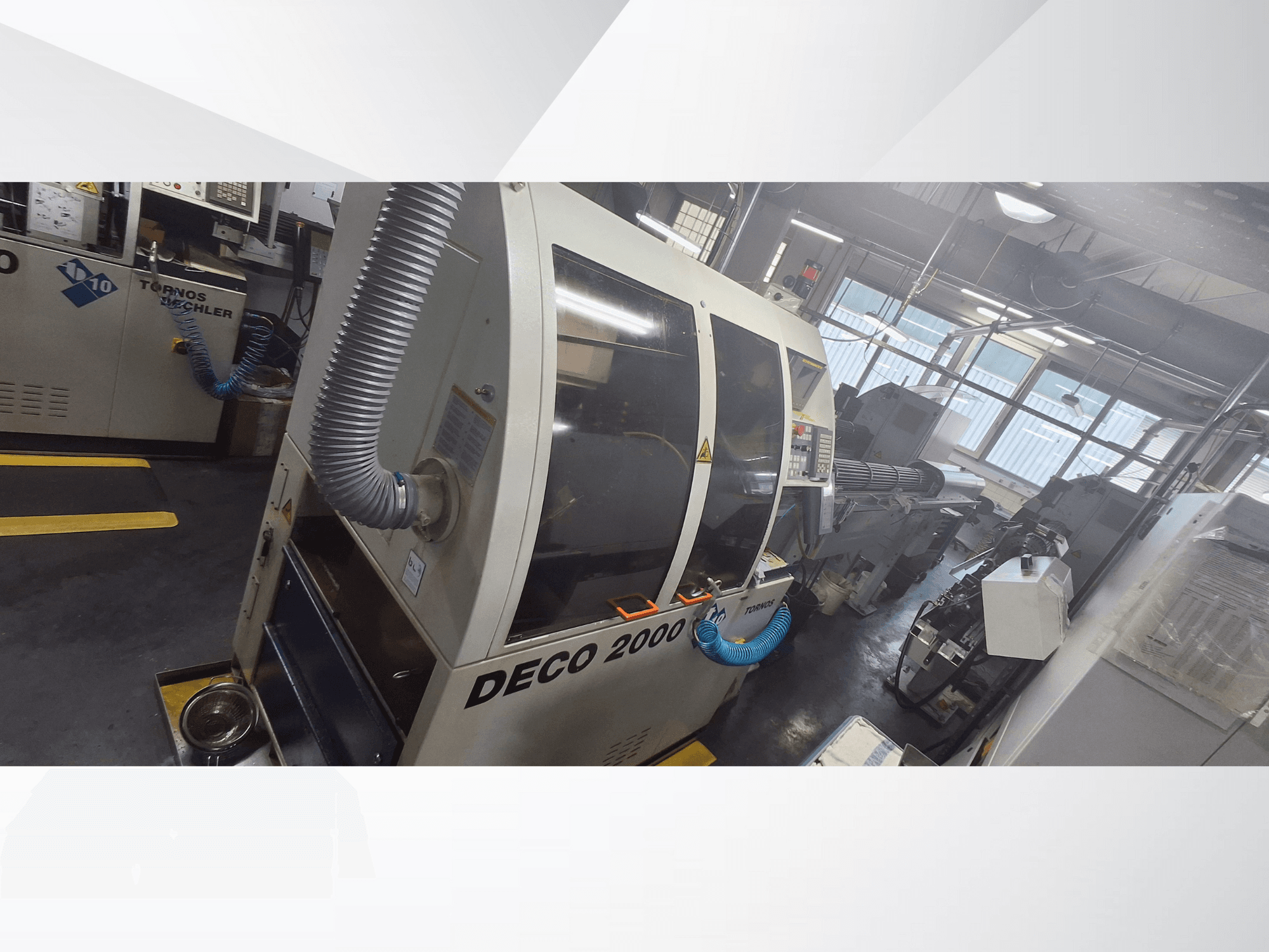 DECO 2000 CNC-Maschine in der Werkstatt, Vorderansicht, mit Lüftungsschlauch und Bedienfeld, konzipiert für Präzisionsbearbeitung.