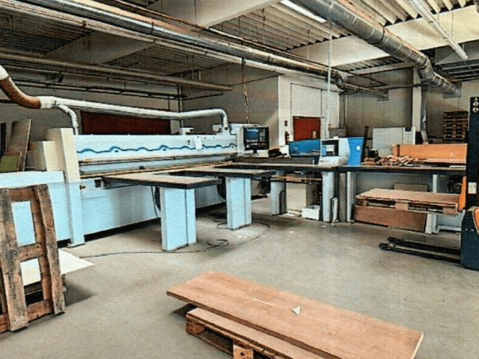 HOMAG HPL 11/38/22 Plattensäge in einer Werkstatt mit großem Schneidtisch und Ausstellungskonsole, von vorne gesehen.