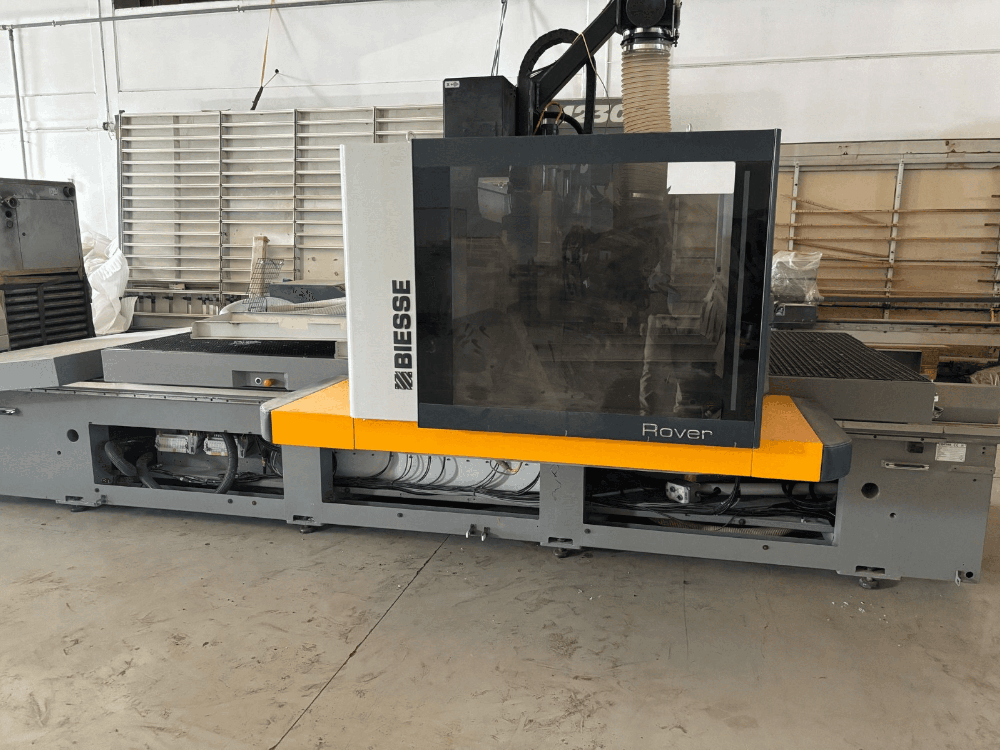 Biesse Rover CNC machining center, front view, features a large control panel, yellow accents, and exposed mechanical components.