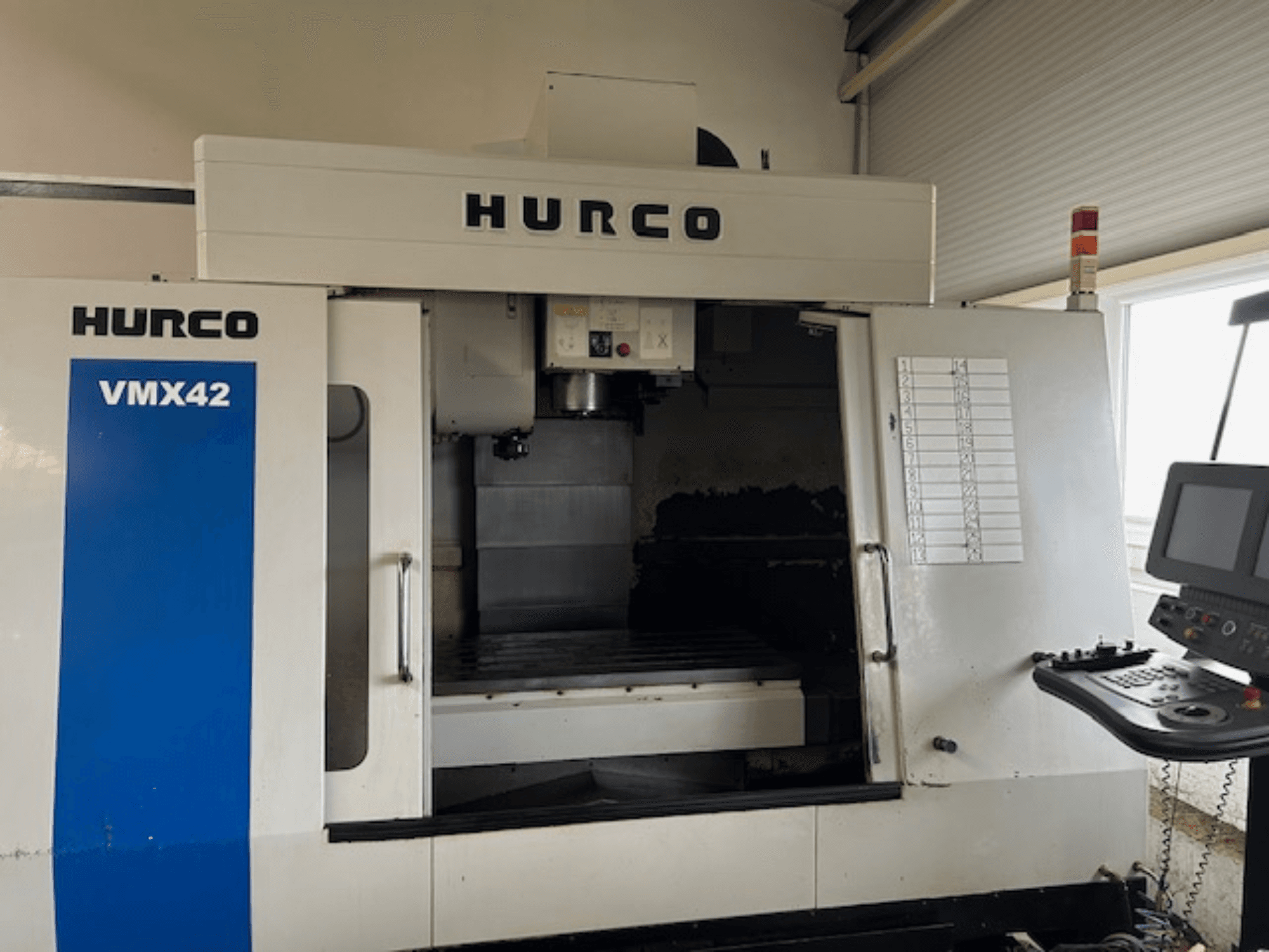 Hurco VMX42 CNC-Maschine in der Vorderansicht, mit Bedienfeld, Spindel und Arbeitsbereich; zeigt das Betriebslayout.