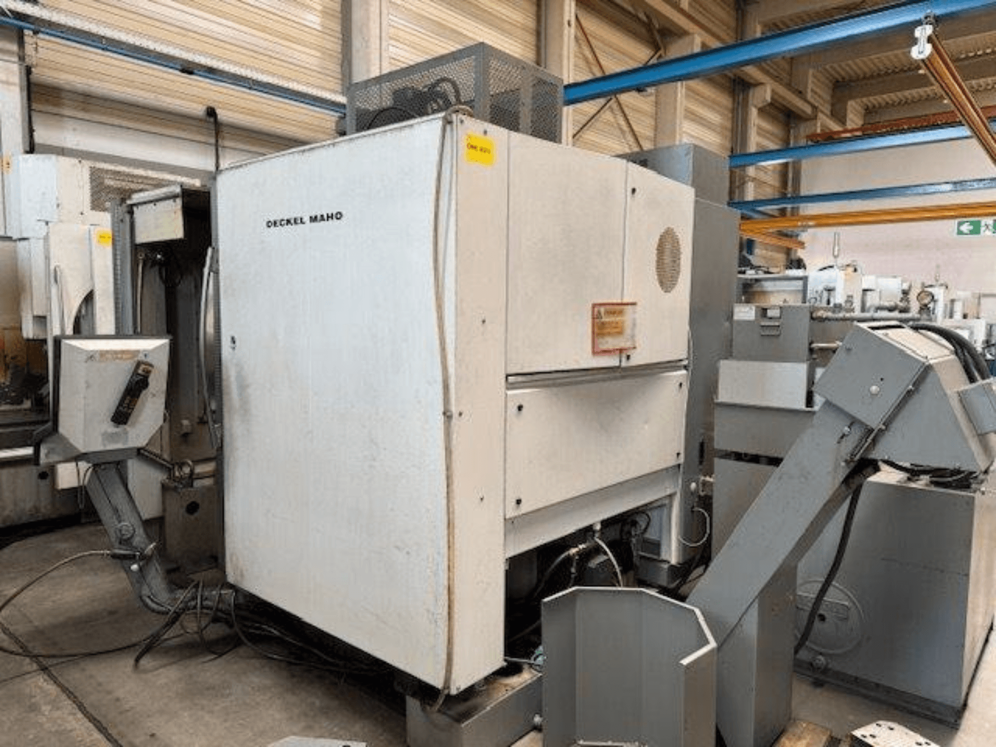 DECKEL MAHO DMC 100 V Vertikal-Bearbeitungszentrum, Seitenansicht mit Bedienpult und verschiedenen Vorrichtungen sichtbar.