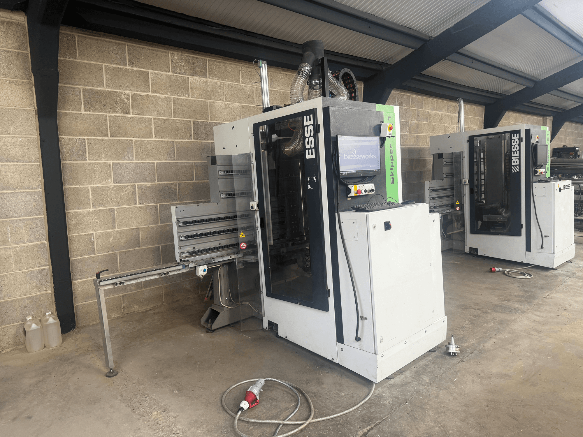 BIESSE Skipper v31 Holzbohrmaschine in der Seitenansicht, mit Bedienfeld und angrenzenden Maschinen, in einer Werkstatt.