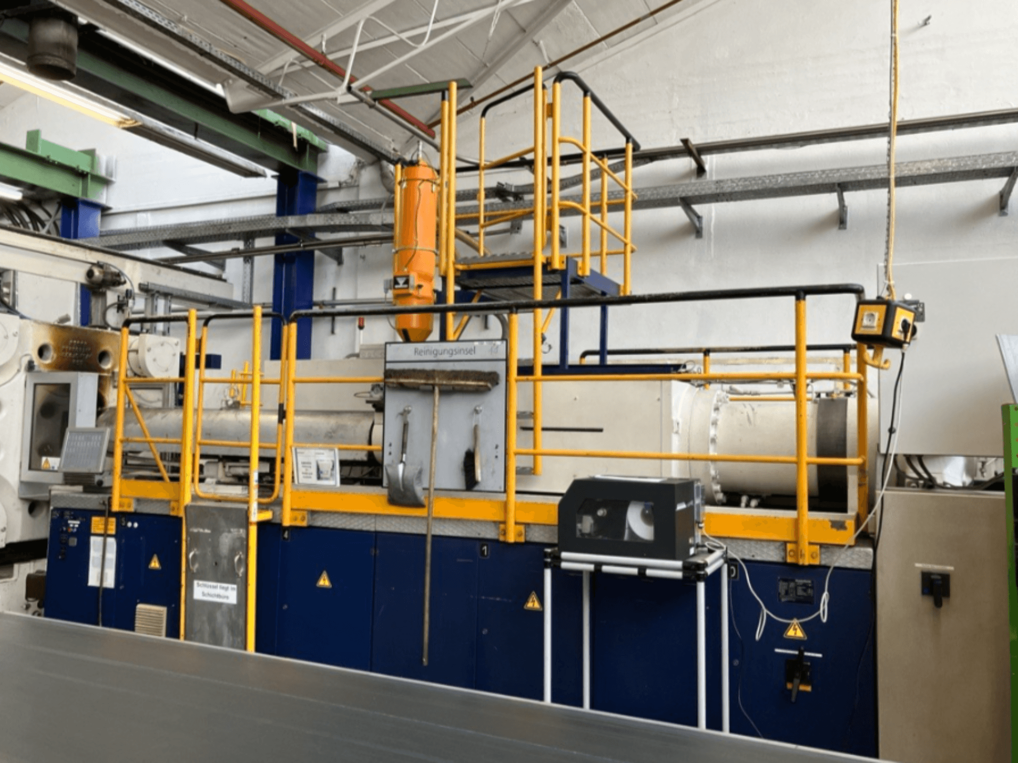 Krauss Maffei 1000-8000 M hydraulische Spritzgießmaschine, Seitenansicht mit Sicherheitsgeländer und Bedienpult sichtbar.