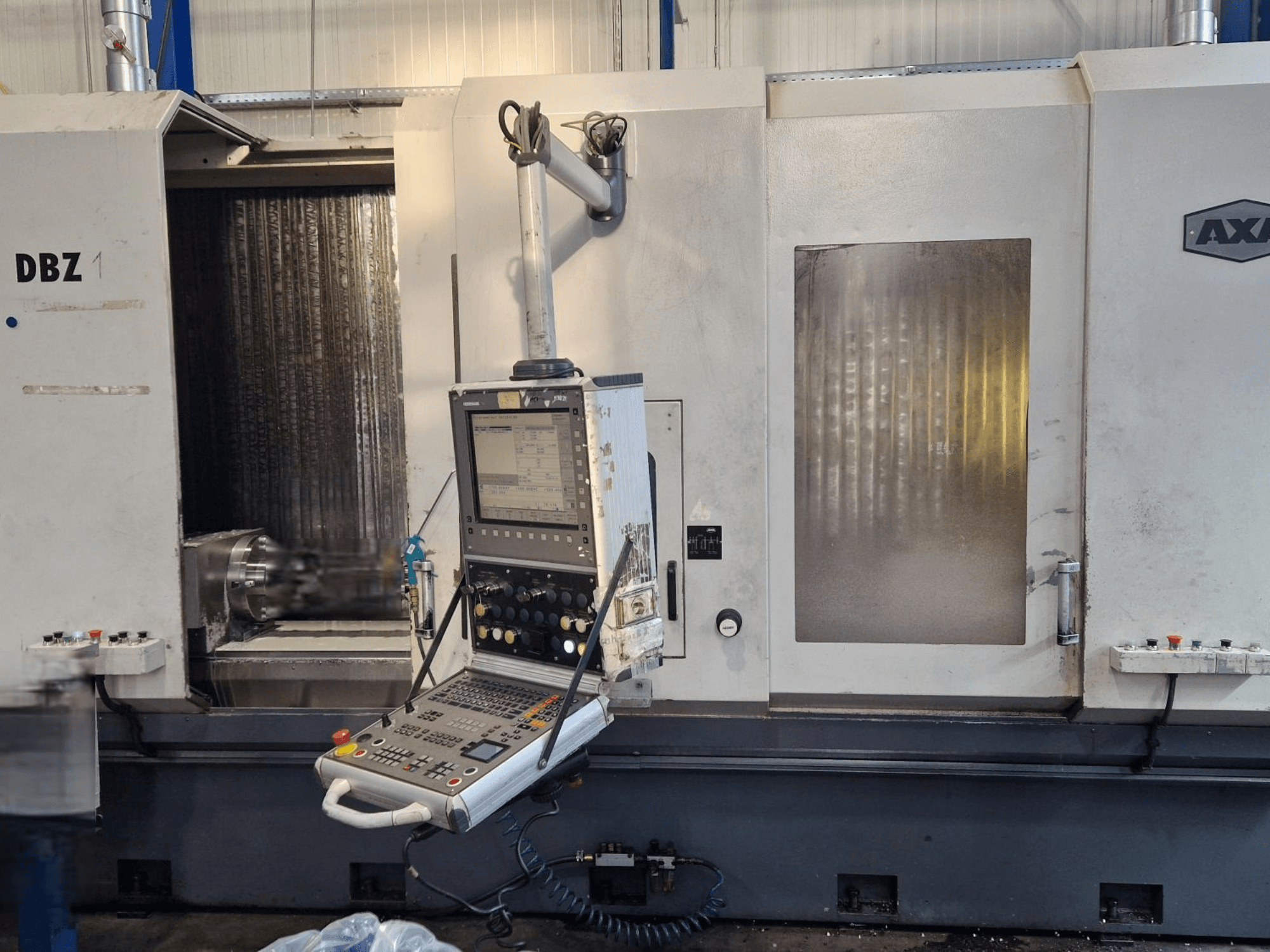 AXA DBZ Vertikal-Bearbeitungszentrum in der schrägen Vorderansicht mit Bedienfeld und sichtbarem Werkzeugbereich.