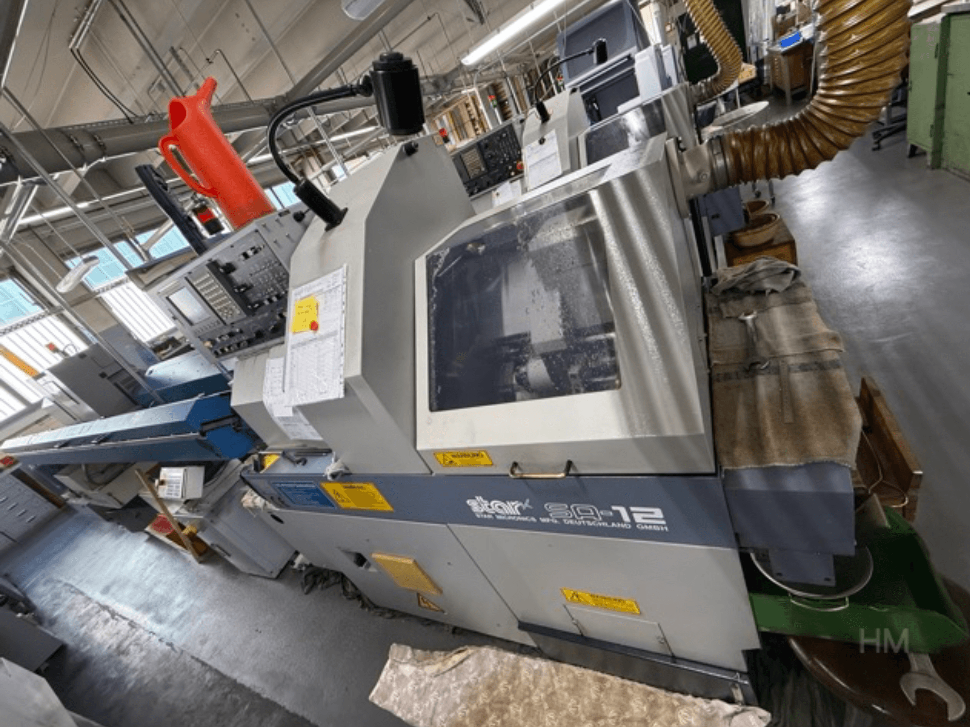 Star SQ-12-Bearbeitungszentrum, Seitenansicht mit Bedienfeld, Kühlmittelbehälter und Staubabsaugschlauch sichtbar.