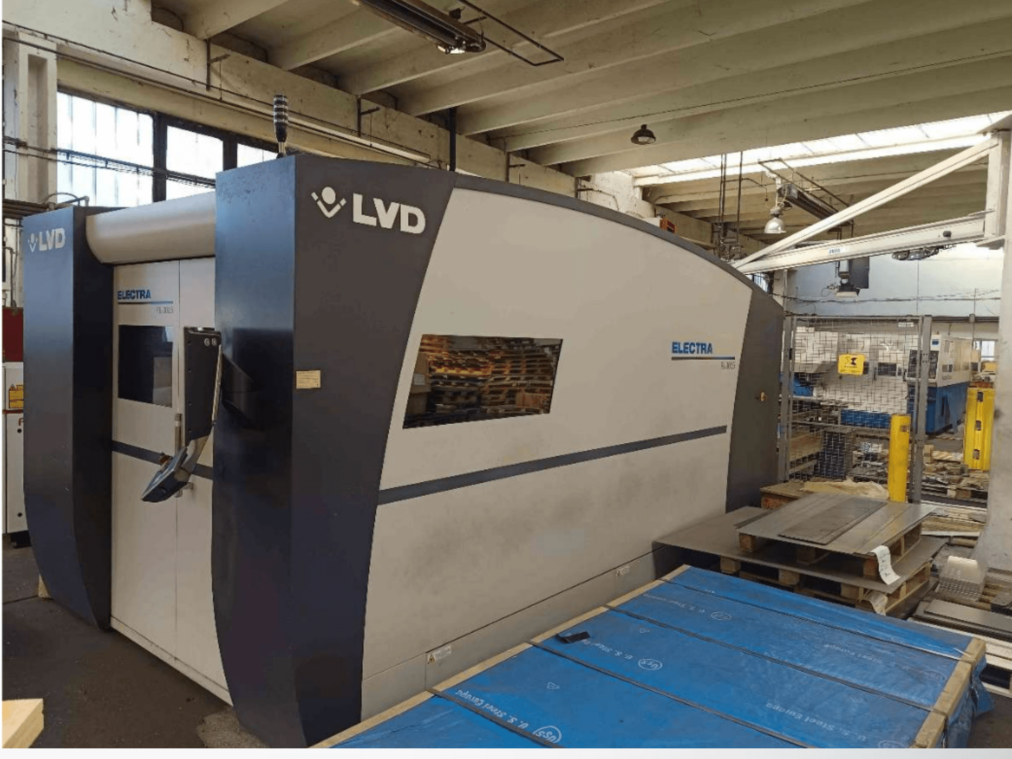 LVD Electra laser cutting machine in side view, features a sleek design and a control panel at the door, placed in a workshop.