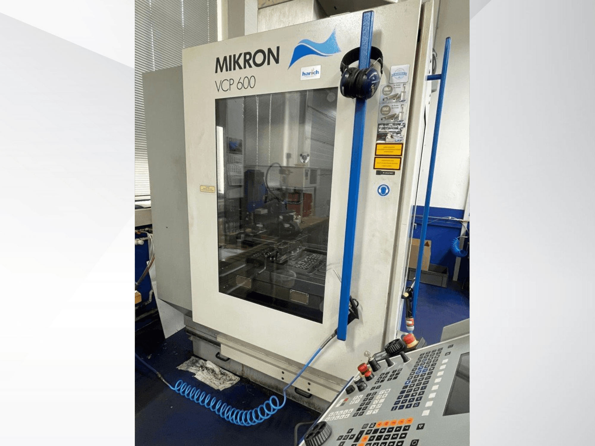 Mikron VCP 600 CNC-Maschine, Vorderansicht, mit Bedienfeld mit Tasten und sichtbarem Bearbeitungsbereich hinter Glas.
