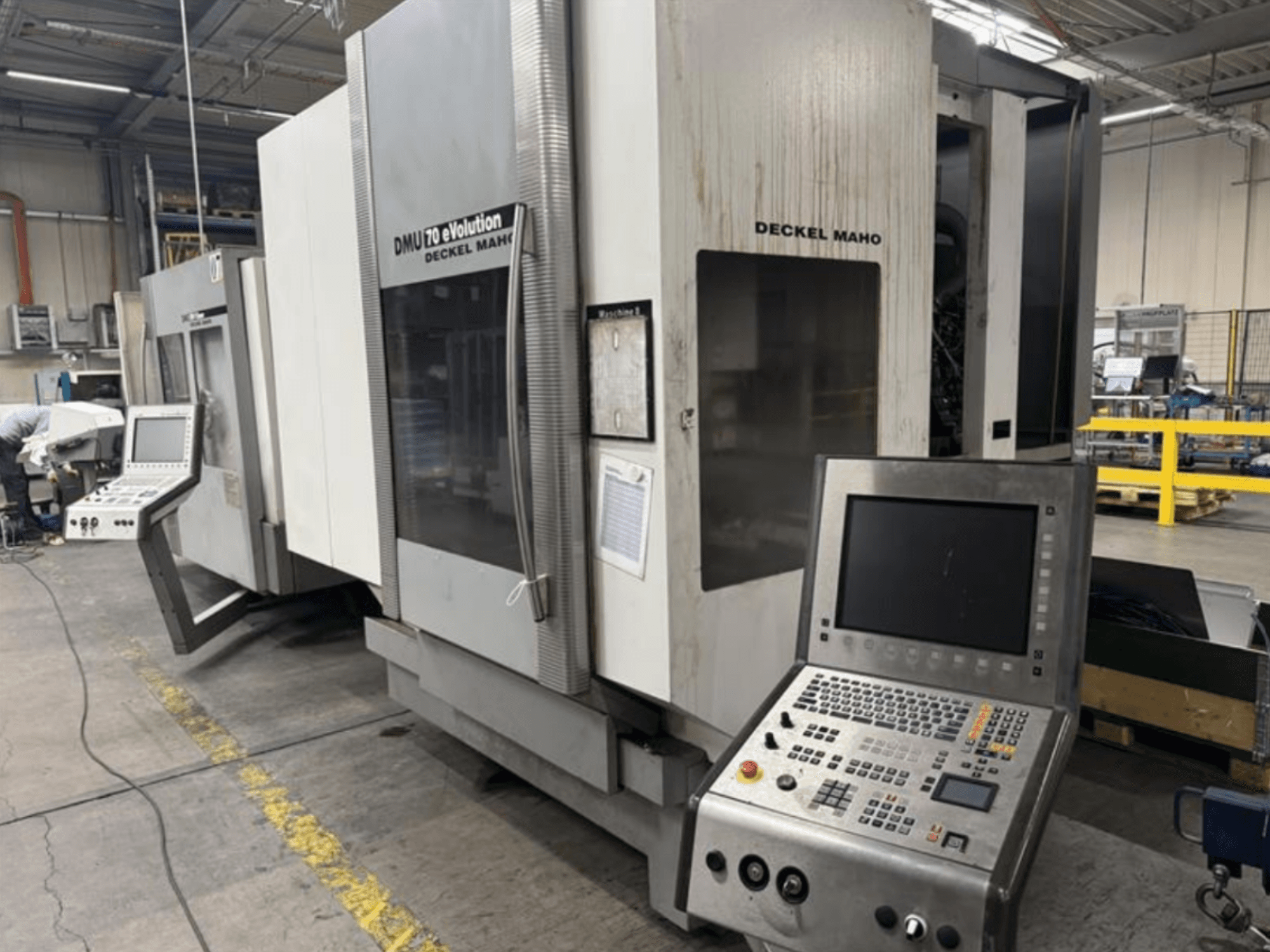 Frontansicht einer Deckel Maho DMU 70 eVOLUTION CNC-Maschine mit Bedienpult in einer Produktionsstätte.