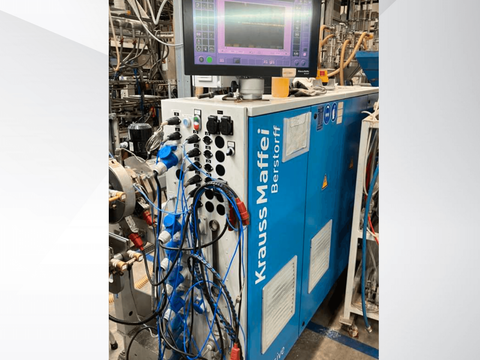 Krauss Maffei Berstorff Industriemaschine mit Bedienfeld und Monitor, mit verschiedenen Tasten und angeschlossenen Schläuchen, Seitenansicht.