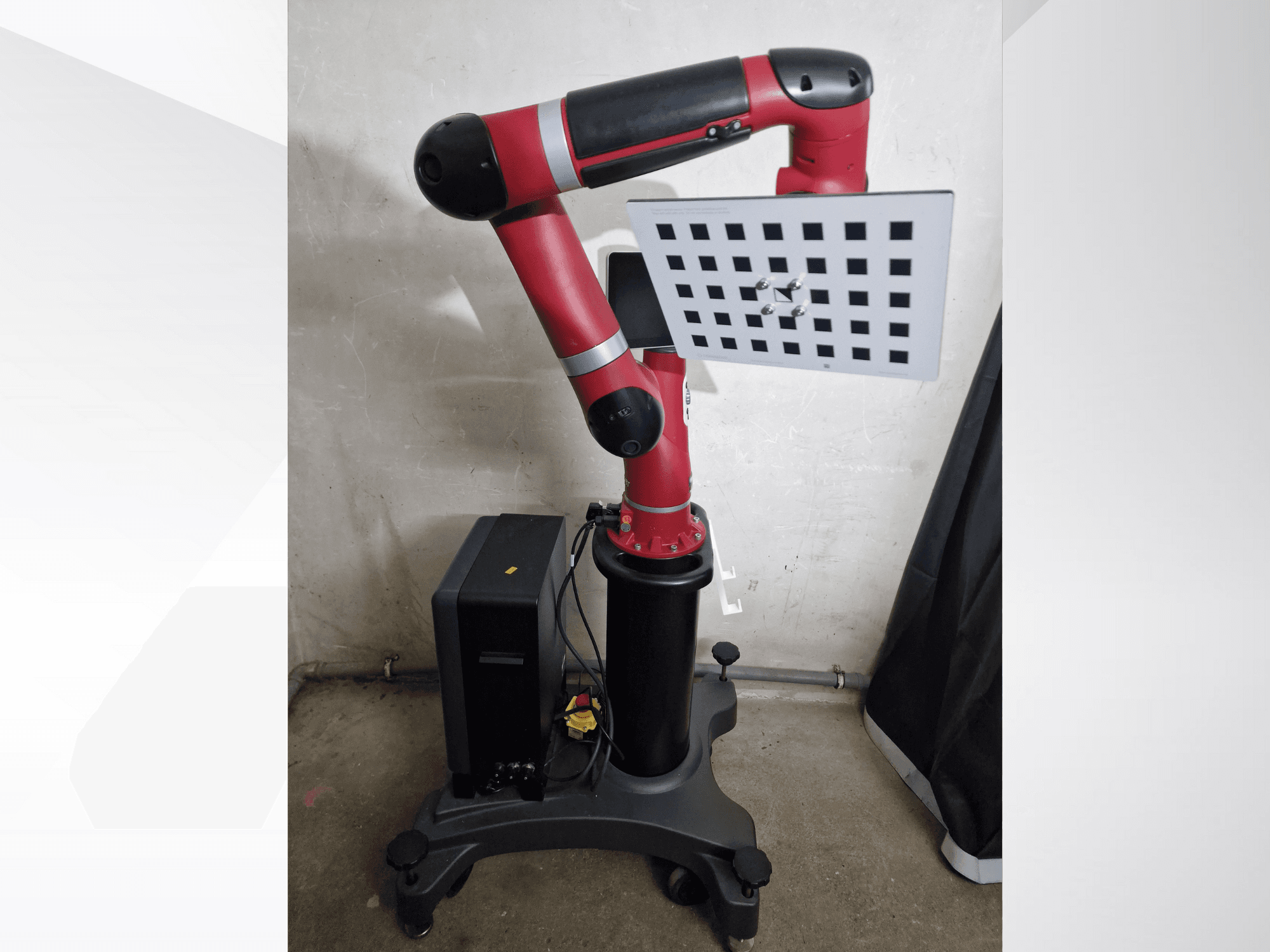 Roter Roboterarm mit rechteckigem Arbeitsbereich, ausgestattet mit einer Gitteroberfläche und montiert auf einem schwarzen Sockel, Seitenansicht.
