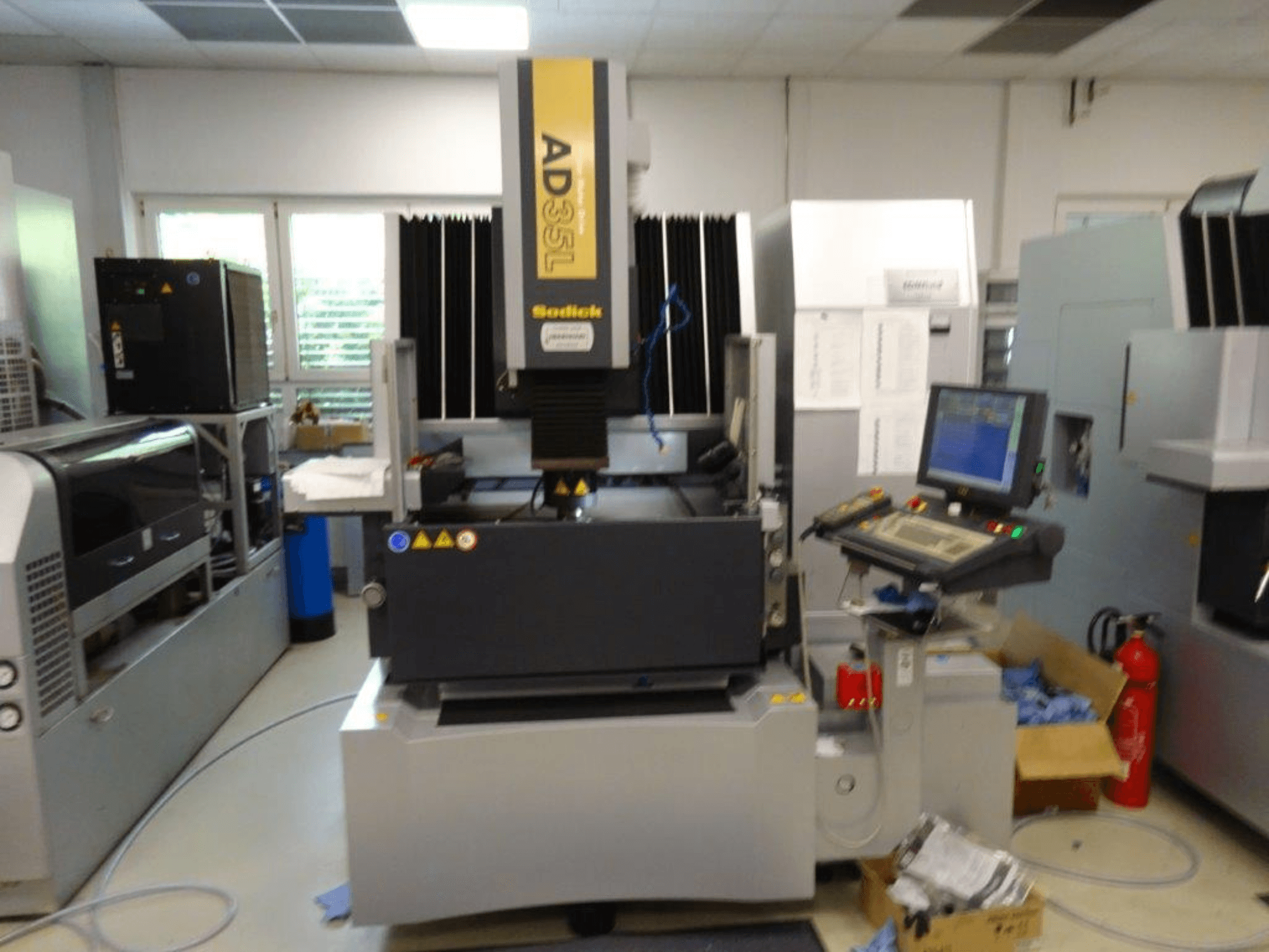 Sodick AD35L CNC-Maschine in der Vorderansicht mit Bedienfeld, Kühleinheit und Sicherheitsanzeigen.