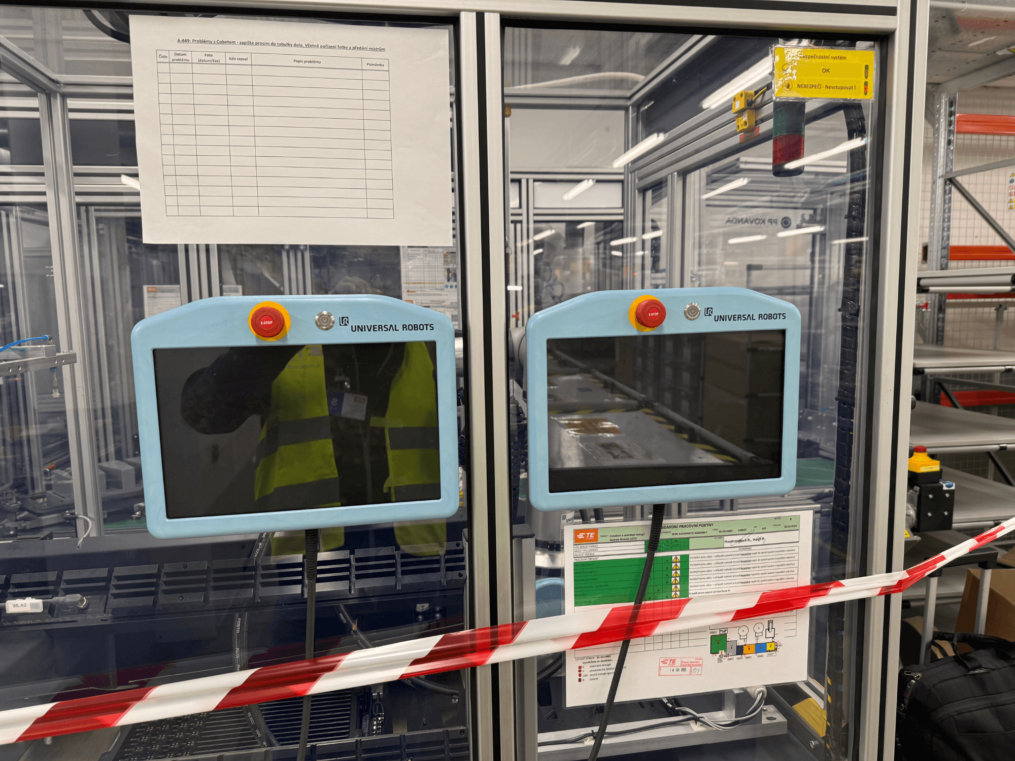 Bedienfeld für den Roboterarm UR5 e von Universal Robots, mit zwei Monitoren, Not-Aus-Tasten und Sicherheitshinweisen.