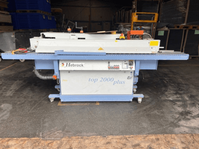 Hebrock Top 2000 Plus, Vorderansicht; elektrische Industriemaschine mit Bedienfeld, Rädern für die Mobilität und sichtbaren Sicherheitsetiketten.