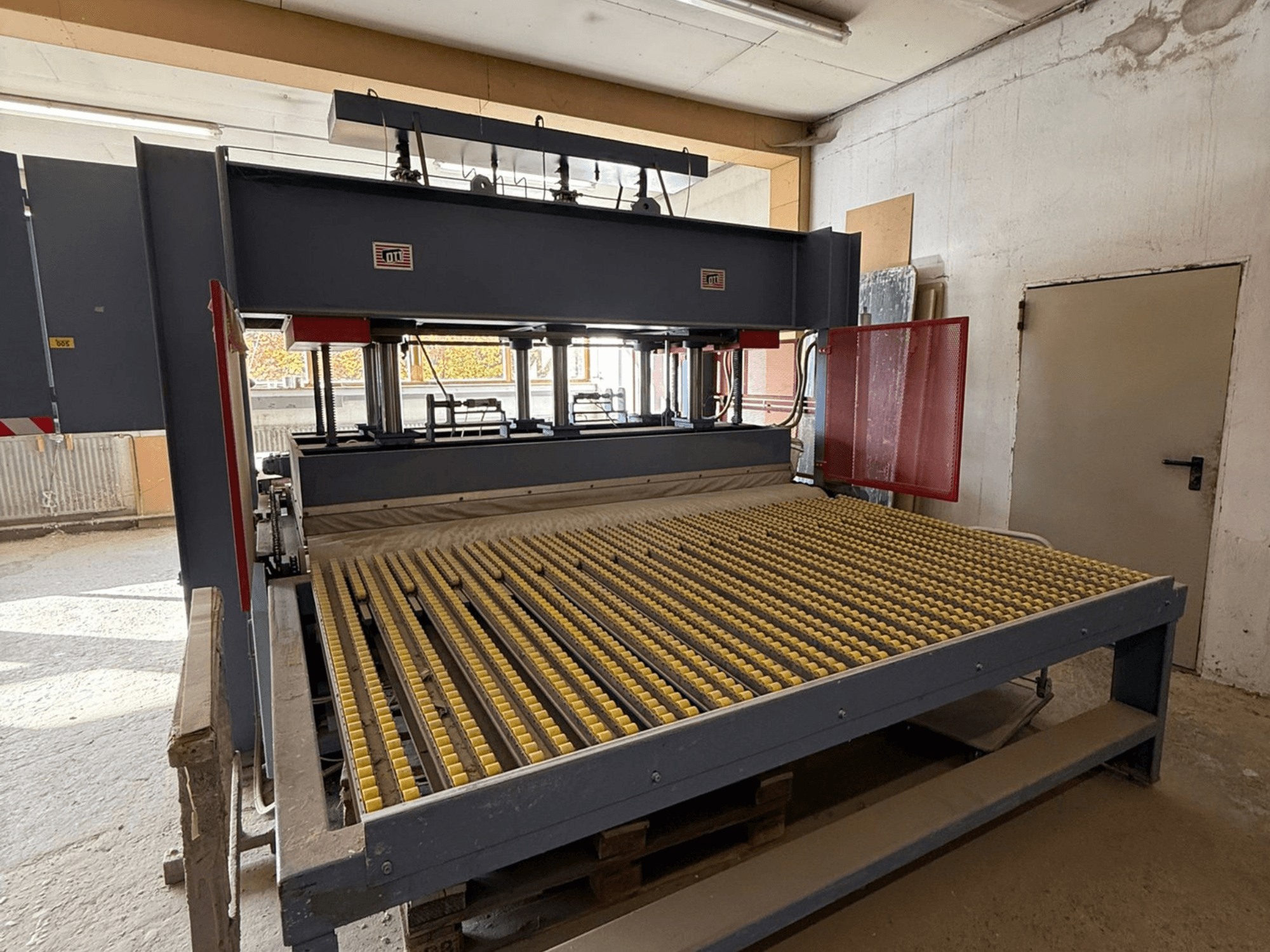 Industriemaschine mit gelben Walzen, Vorderansicht, Markenlogo sichtbar, für die Bearbeitung von Materialien in einer Werkstatt.