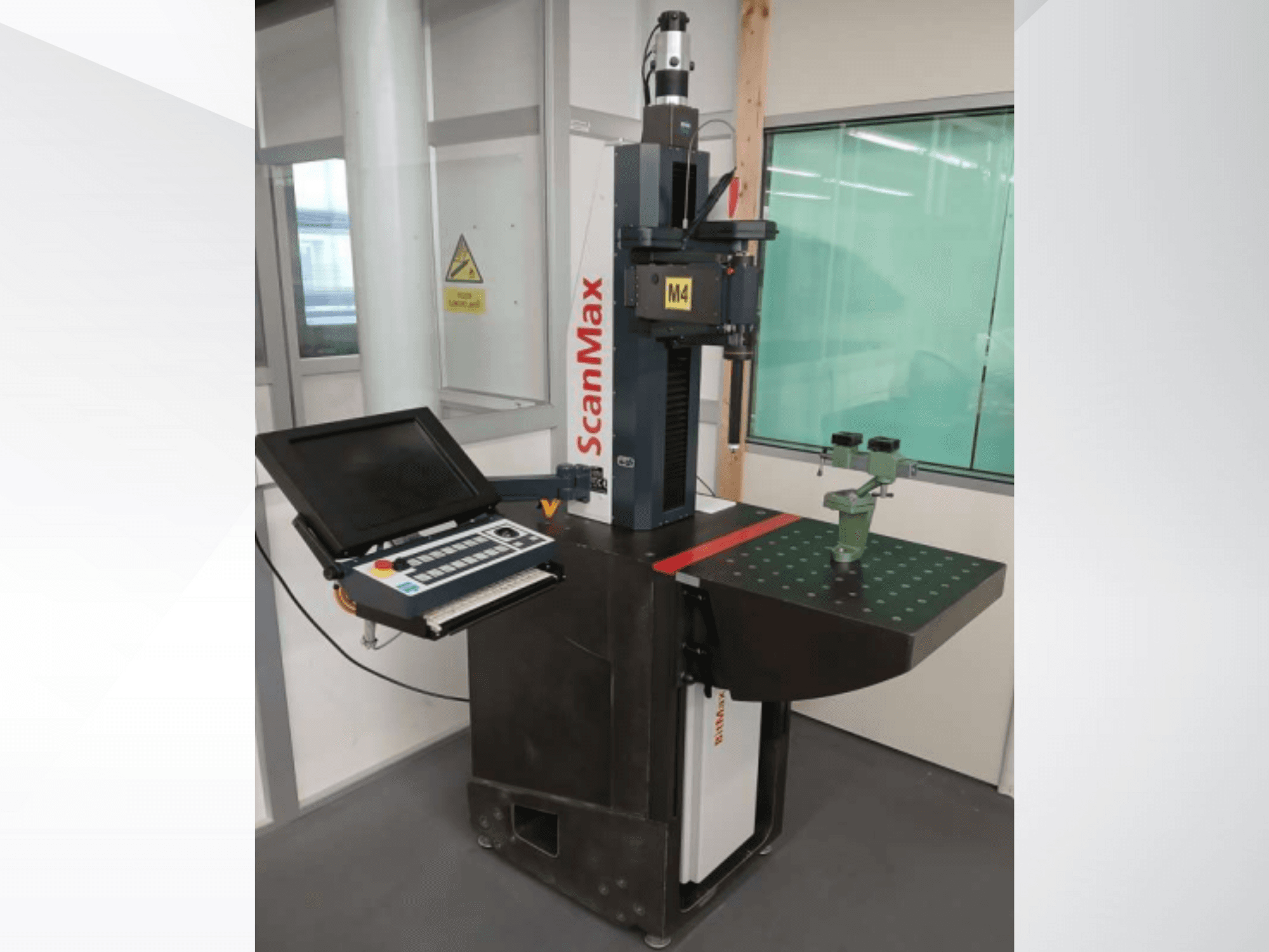 ScanMax M4 Messmaschine, Vorderansicht mit Bedienfeld und grüner Kalibriervorrichtung auf einem gepunkteten Arbeitstisch.