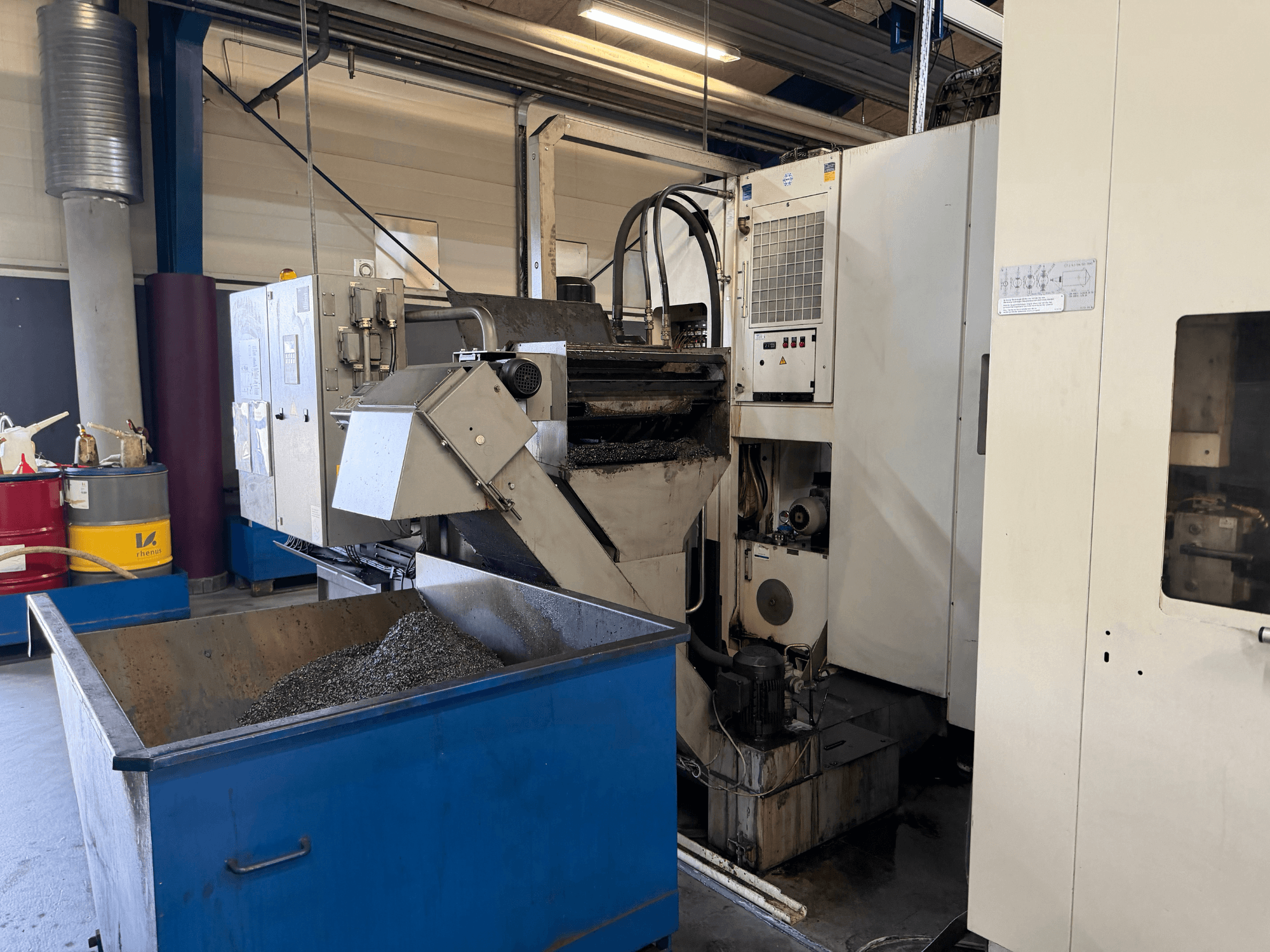 Frontansicht des Horizontal-Bearbeitungszentrums HELLER MCH 250 mit Metall-Kühlmittel-Recycling-Behälter und Bedienfeld sichtbar.