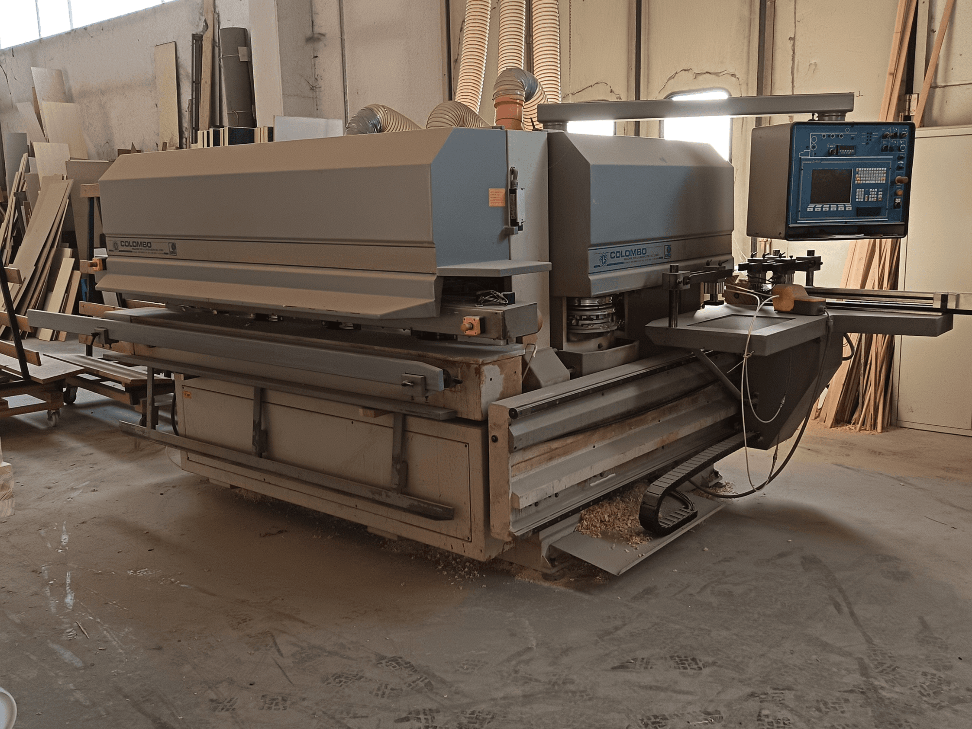 Colombo-Holzbearbeitungsmaschine, Seitenansicht, mit Bedienfeld, Schneidblättern und Sägestaubansammlung in der Werkstatt.