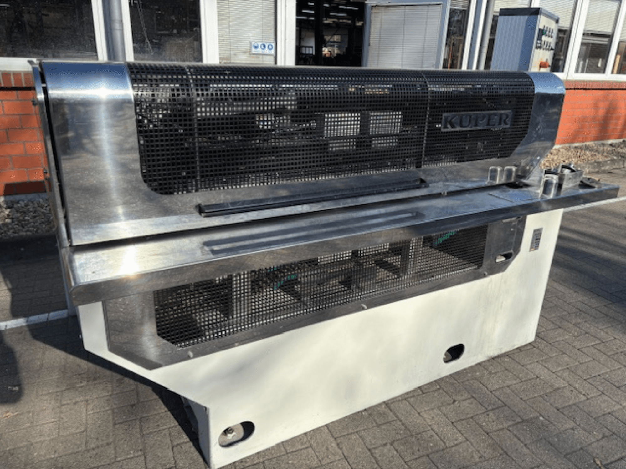 KUPER FLI Furnierschneidemaschine, Vorderansicht, mit Edelstahlgehäuse und Schutzgitter für sicheren Betrieb.