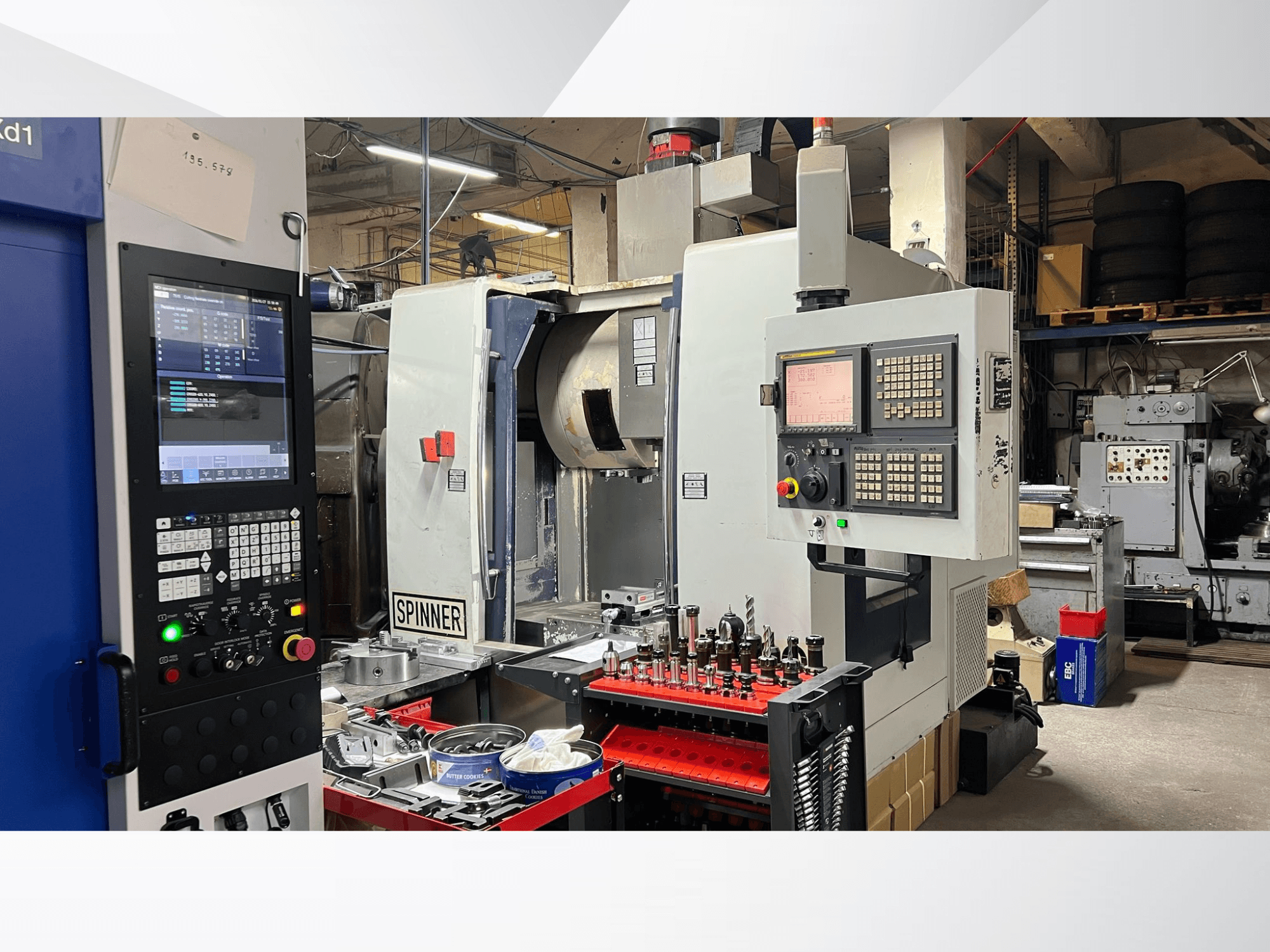 CNC-Maschine mit Bedienfeld, Werkzeugen und Werkstücken, von vorne gesehen in einer Werkstattumgebung.