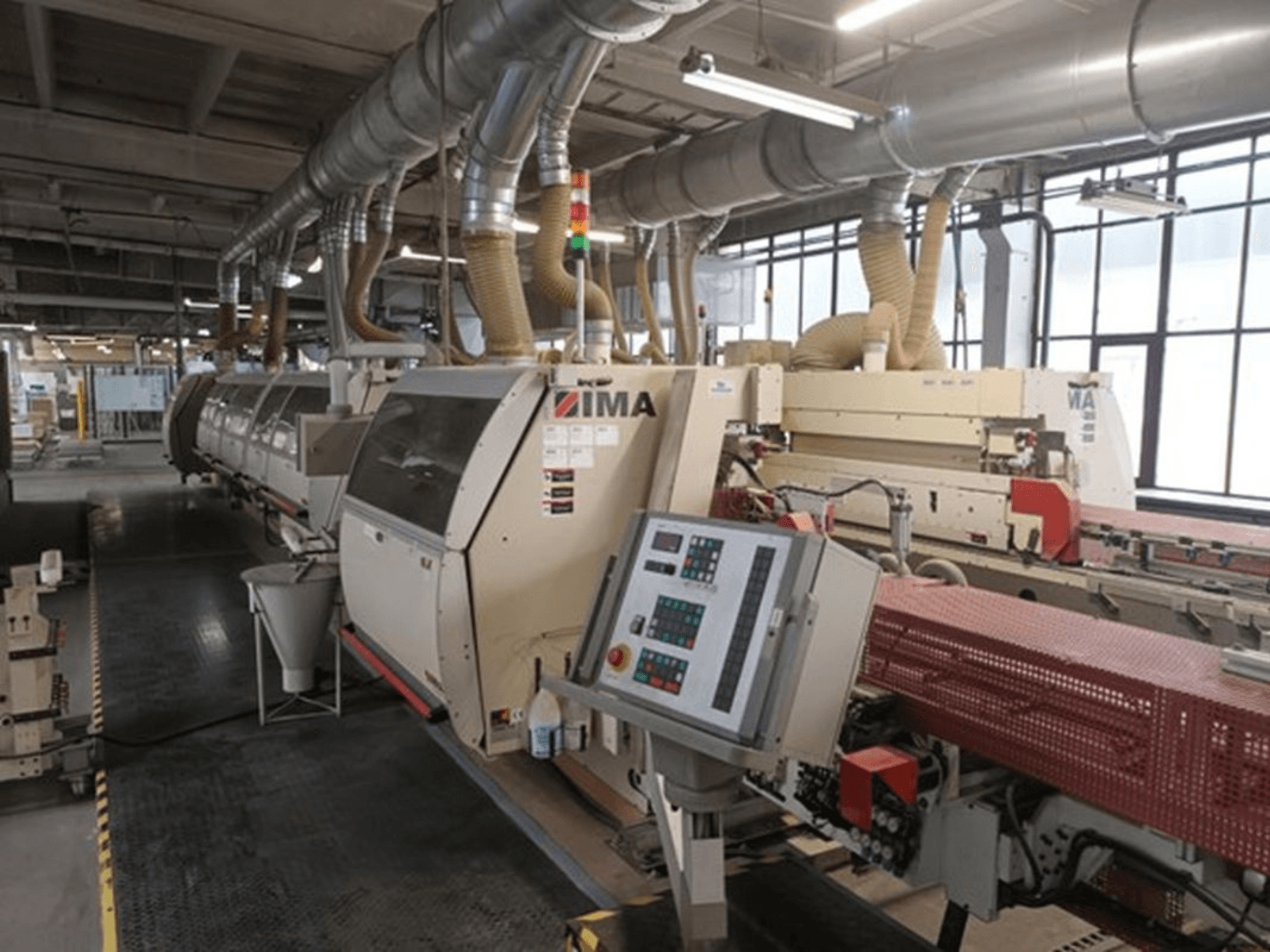 IMA industrial machinery in a factory setting, front view, featuring control panels and dust extraction pipes.