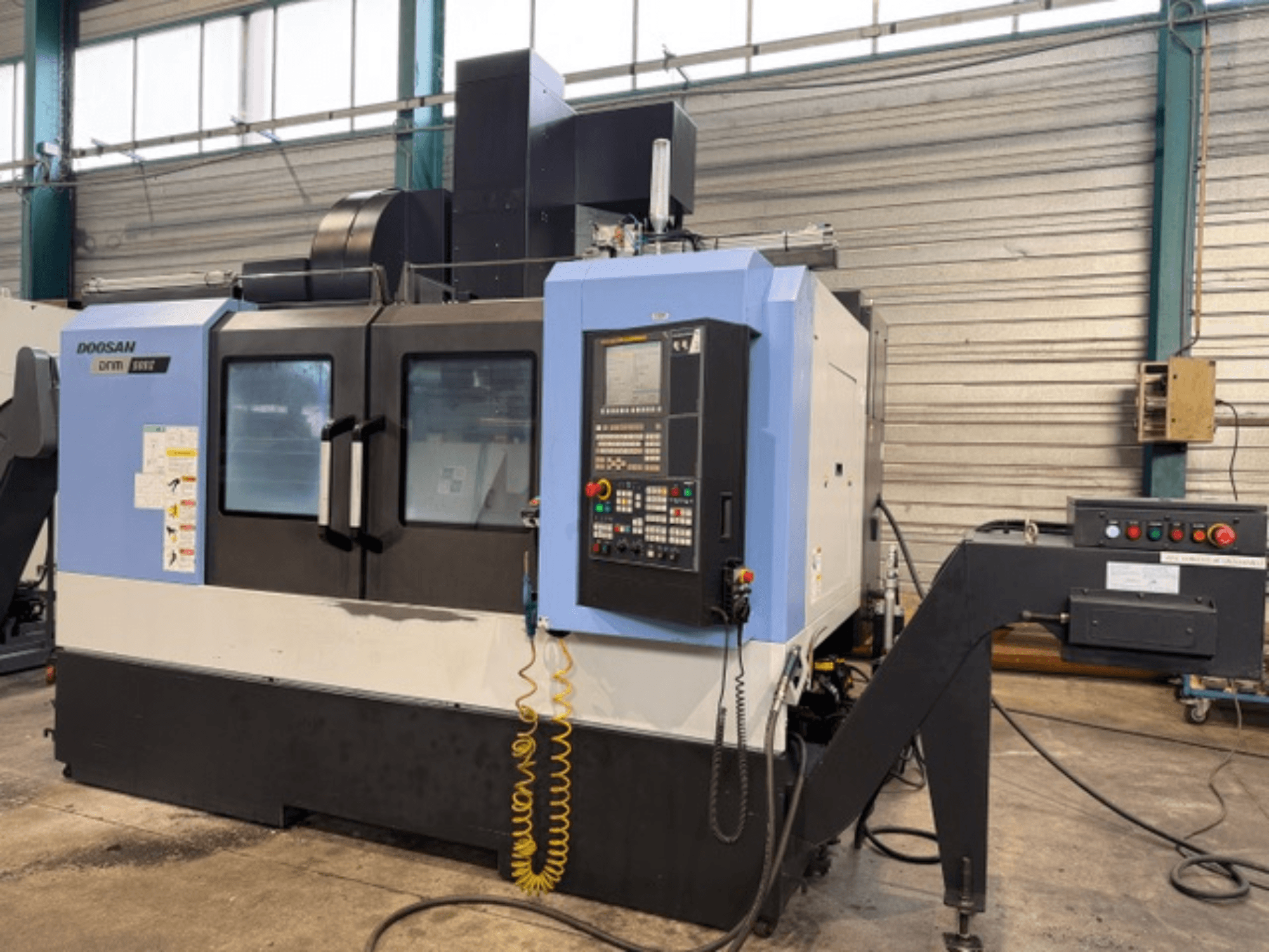 Doosan DNM 500II CNC-Fräsmaschine in der Vorderansicht mit Bedienfeld und Werkzeughalter in einer Fabrikumgebung.
