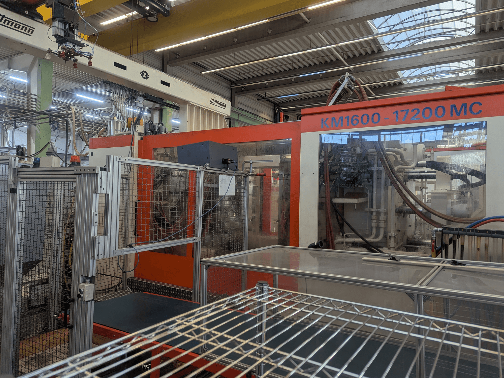 Hydraulische Spritzgießmaschine Krauss Maffei KM 1600-17200MC, Frontansicht mit sichtbarem Bedienfeld und Hydraulikleitungen.