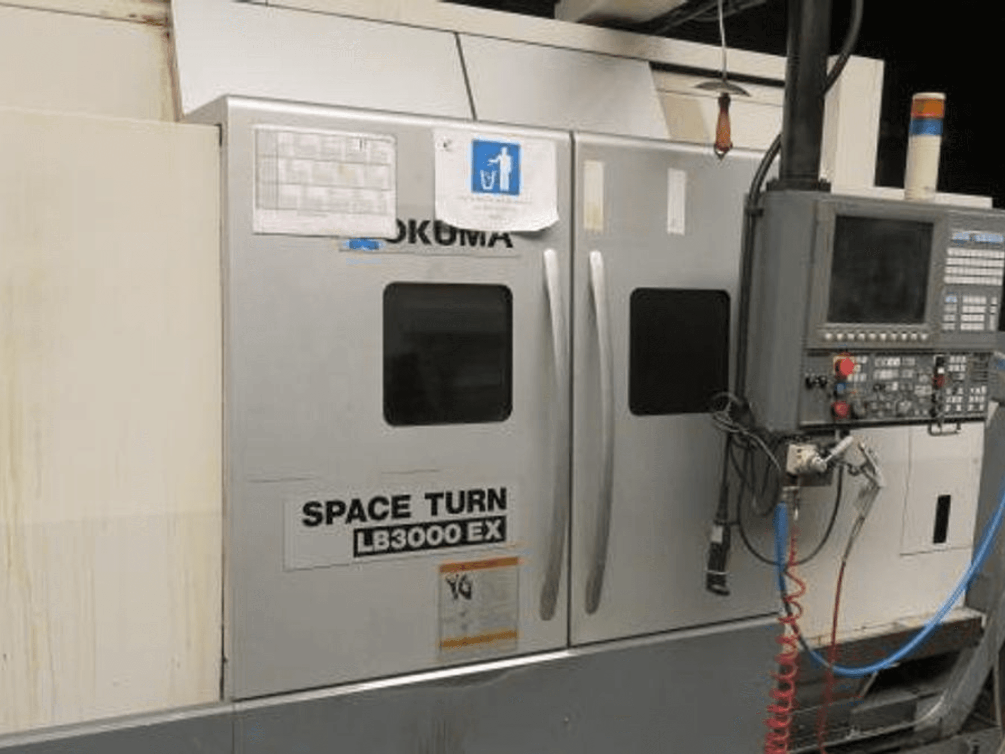 Okuma Space Turn LB3000 EX CNC lathe, side view, featuring control panel, two doors, and visible wiring.