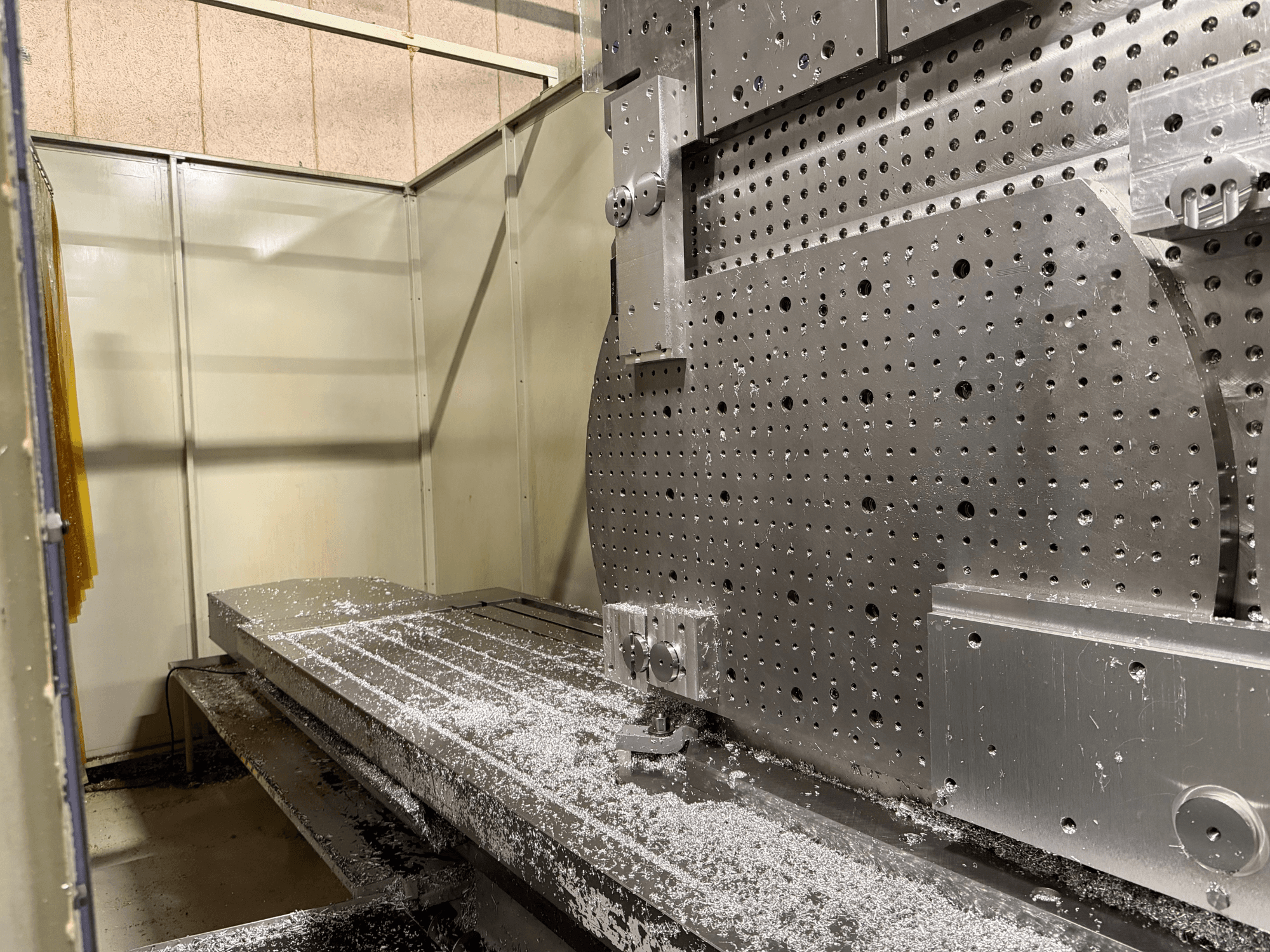 Nahaufnahme der Vorderseite des KIHEUNG Universal-Bearbeitungszentrums KNC-U1000, die einen Metallarbeitstisch mit Aluminiumspänen zeigt.